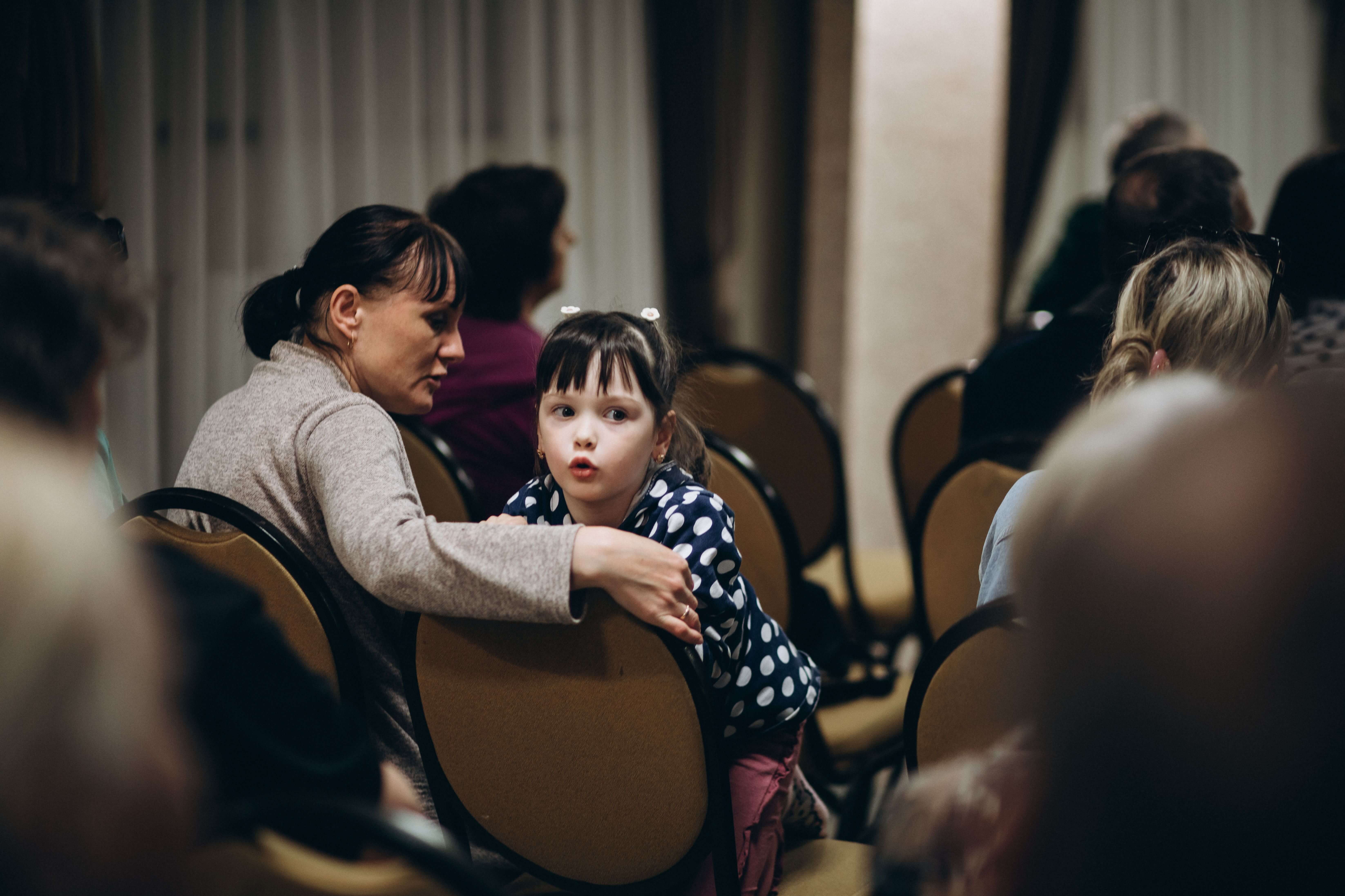 Volunteers hold two infant twins as their parents eat at MWB food distribution point in Ukraine