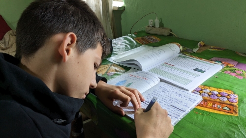 Alin doing homework with his new school supplies